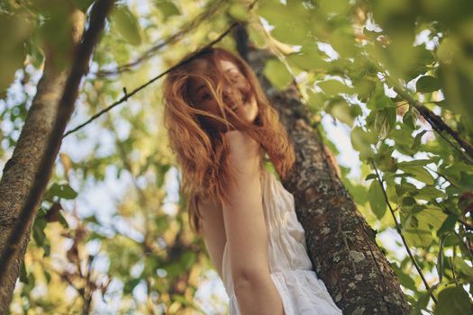 joyful red-haired woman in the forest near the tree nature summer. High quality photo