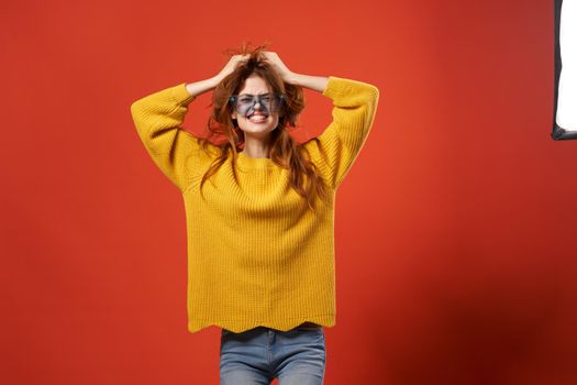 pretty woman in yellow sweater fashion glasses red background. High quality photo