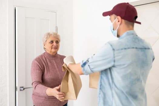 An elderly woman in a medical mask stays at home. Food delivery to the elderly.