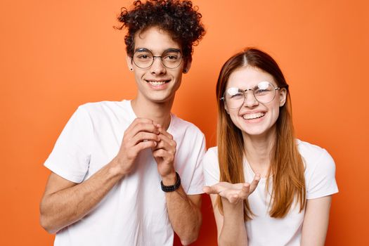 cheerful young couple in white t-shirts together friendship orange background. High quality photo