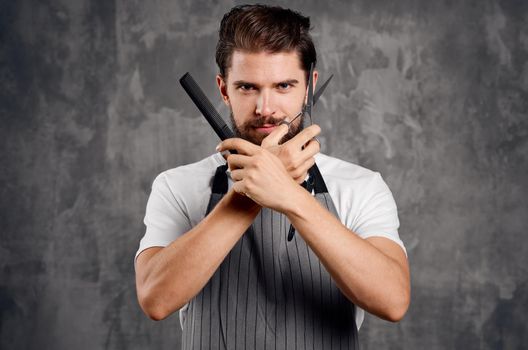 male hairdresser in an apron with a comb in his hands and scissors. High quality photo