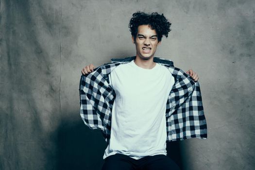 cute guy in a plaid shirt sitting on a chair posing studio. High quality photo