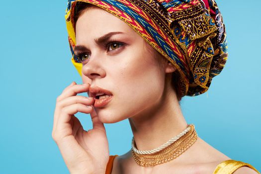 beautiful woman in multicolored turban attractive look Jewelry smile blue background. High quality photo