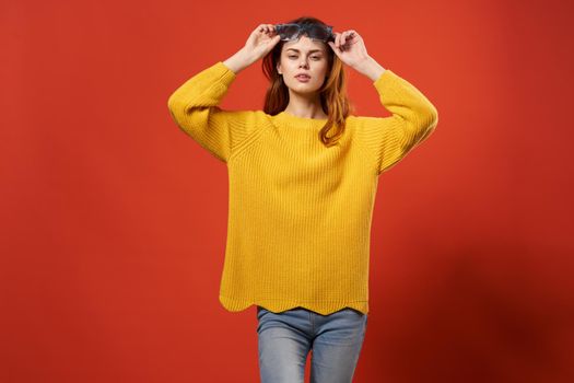 pretty woman in yellow sweater fashion glasses red background. High quality photo