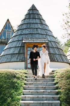 Bride and groom go down the stairs near the cone house. High quality photo