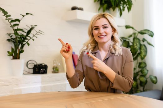 Advertisement concept. Positive, pretty, caucasion woman is pointing with her two index finger