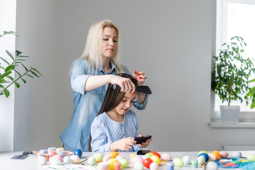 Happy family preparing for Easter. mom combing daughter.