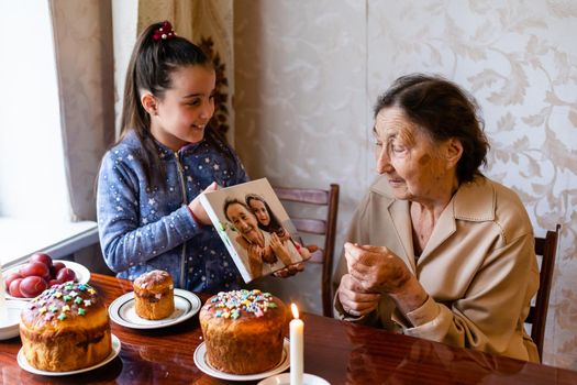 very old grandmother and granddaughter color eggs, preparing Easter cake for Easter at home