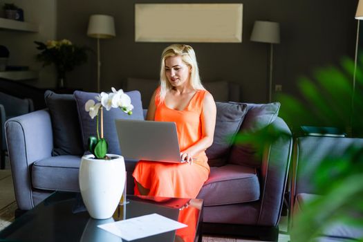 Young woman sitting on sofa at hotel lobby working laptop computer.