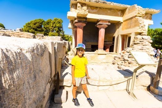 A little girl stops to take a photo of artwork on the walls of the Minoan palace at Knossos. Crete, Greece.