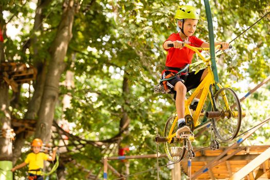 Cute school boy enjoying a sunny day in a climbing adventure activity park.