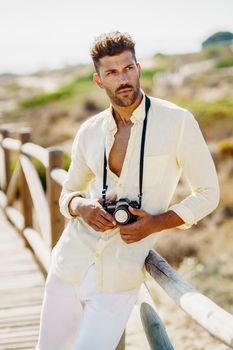 Handsome man photographing in a coastal area with an SLR camera