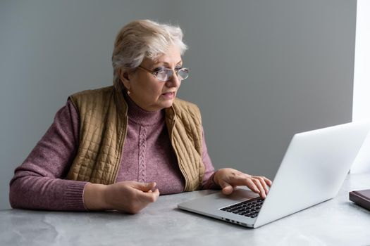 Elderly woman having a video call with her family, smiling and waving. Quarantine time.