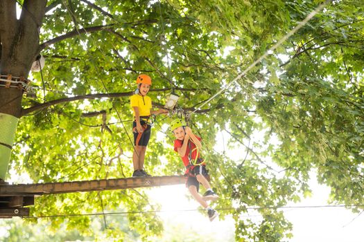 Happy child climbing in the trees. Rope park. Climber child. Early childhood development. Roping park. Balance beam and rope bridges. Rope park - climbing center.