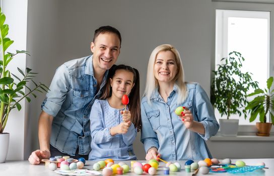 Happy easter family mother, father and children having fun paint and decorate eggs for holiday.