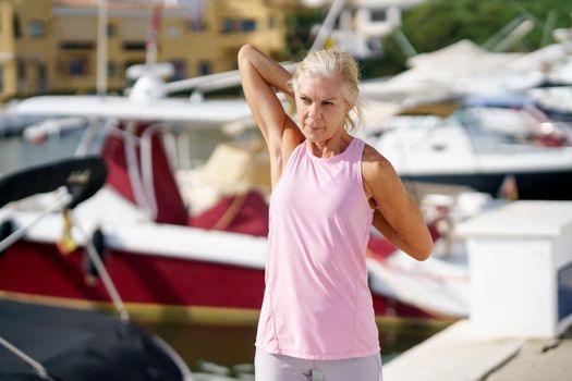 Mature sportswoman stretching her arms after exercise. Concept of healthy living in the elderly. Senior woman in fitness clothing. Older female doing sport to keep fit.