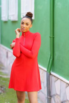 Portrait of a beautiful young black woman in red dress in front of a green wall