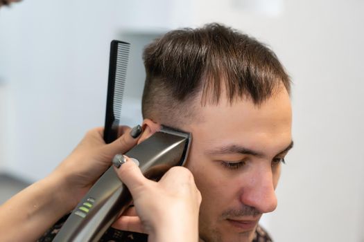 Barber cutting hair with clipper, hairdressing
