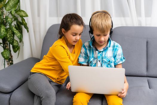 Kids playing with laptop computer at home.