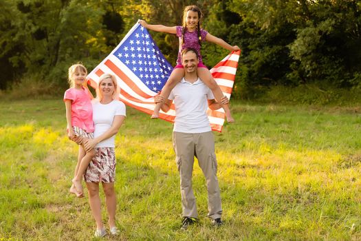 happy family with the flag of america USA at sunset outdoors.