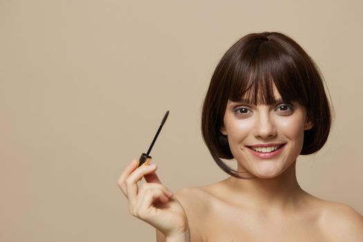 beautiful woman Mascara cosmetics attractive look posing beige background. High quality photo