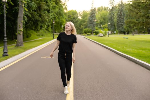 Attractive young woman walks along the line of the road enjoying nature