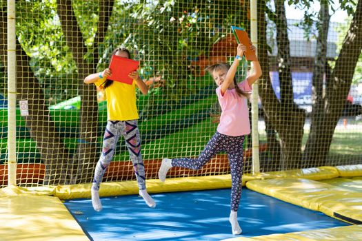 two girls jumping on a trampoline on a summer day