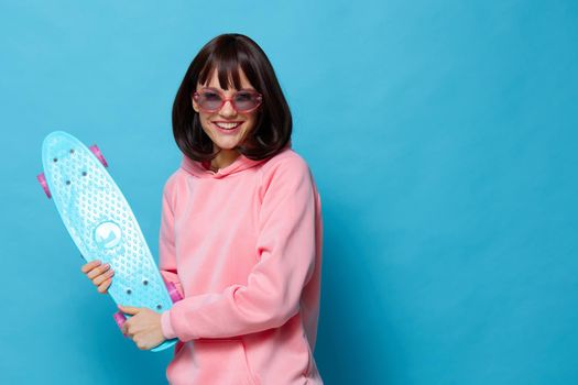 woman in a pink sweater skateboard entertainment blue background. High quality photo