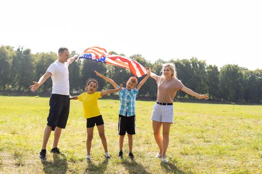 Beautiful family with the American flag in a field. Independence Day, 4th of July