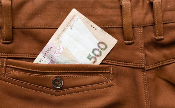 Ukrainian hryvnia in the pocket of brown trousers.