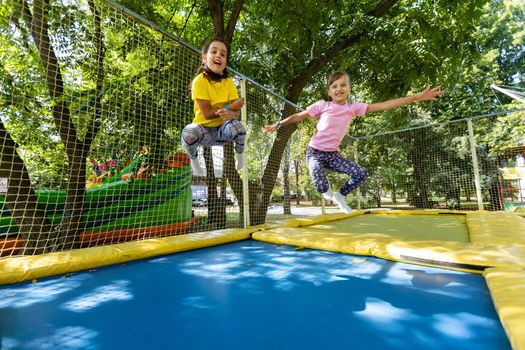 two girls jumping on a trampoline on a summer day