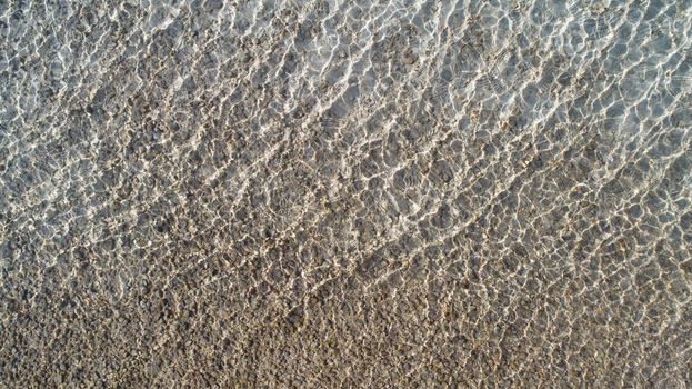 ripples of water showing the random light patters on rocks in the water