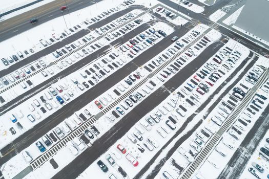 aerial view of a lot of cars in a parking lot and many are covered in snow