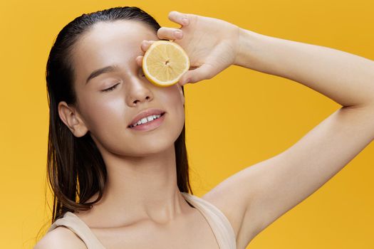 brunette eating lemon in hands smile vitamins diet yellow background. High quality photo