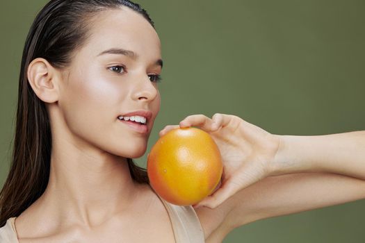 portrait woman with grapefruit near face clean skin care health green background. High quality photo