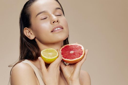 brunette grapefruit near face clean skin care health beige background. High quality photo