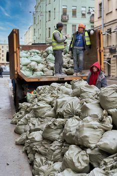 SAINT PETERSBURG, RUSSIA - APRIL 27, 2021: Workers load bags of construction waste into a truck
