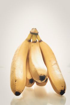 Bunch of ripe yellow bananas on white background. Close up, vertical shot