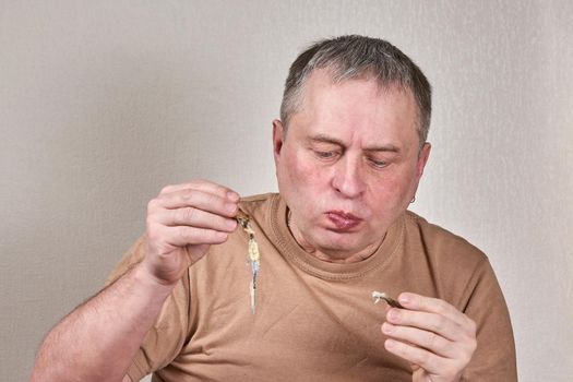 Man eating fried smelt fish holding fish with hands in front of face. Close up