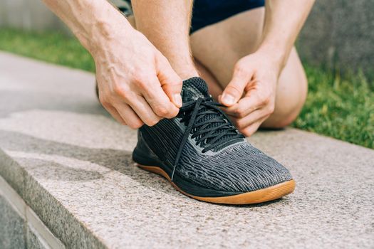 Close up sports man tying shoelace while running outdoors.