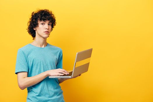 man in blue t-shirts with laptop internet yellow background. High quality photo