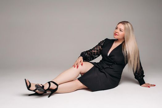 handsome caucasian female with blonde hair posing to the camera in black dress in studio