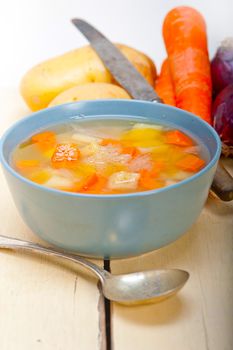 Traditional Italian minestrone soup on a rustic table with ingredients