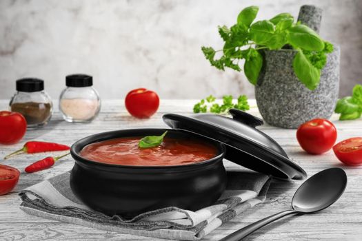 Traditional tomato cream soup and food ingredients on wooden table.