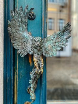 Turquoise wooden and glass entrance with antique door handle in the form of a bird. Unusual details of ornate door. Vintage iron door knob