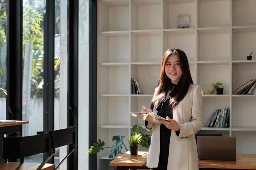 Portrait of business asian woman happy smile holding check list on clipboard and pen at modern offlice.