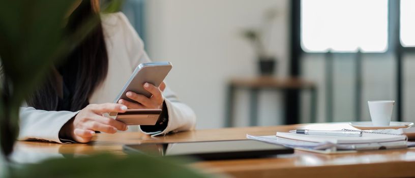 Young woman holding credit card and using smart phone for online shopping. Online payment shopping concept. copyspace banner.