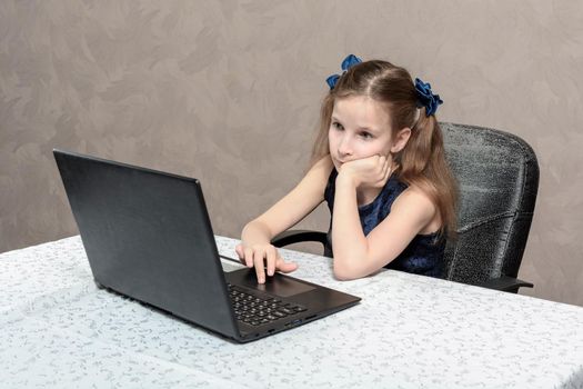 Teen schoolgirl 9 years old of european appearance does her homework on laptop