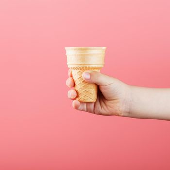 Waffle ice Cream Cup in a child's hand on a pink background. Minimalistic concept, free space for text.