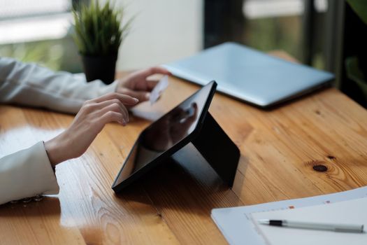 Woman hand holding credit card and using digital tablet at home, Businesswoman or entrepreneur working, Online shopping, e-commerce, internet banking, spending money, working from home concept